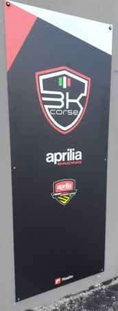 Insegna in Dibond® stretta e alta fissata a muro, in tinta nera con dettagli bianchi e rossi e il logo di "BK Corse"